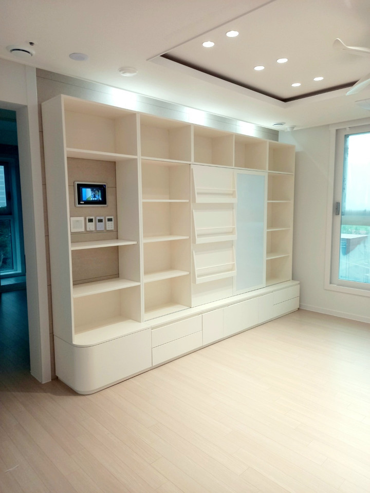 맞춤형 거실 앞 책장 서재형 거실 주방 반원형 테이블 실내 회색 벽지 차분하고 실용적인 실내 공간